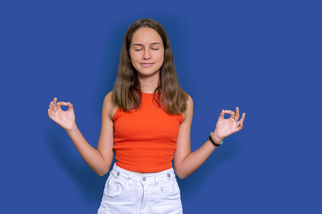 Chica adolescente meditando con ojos cerrados y expresión serena, representando el alivio de la ansiedad y el perfeccionismo excesivo