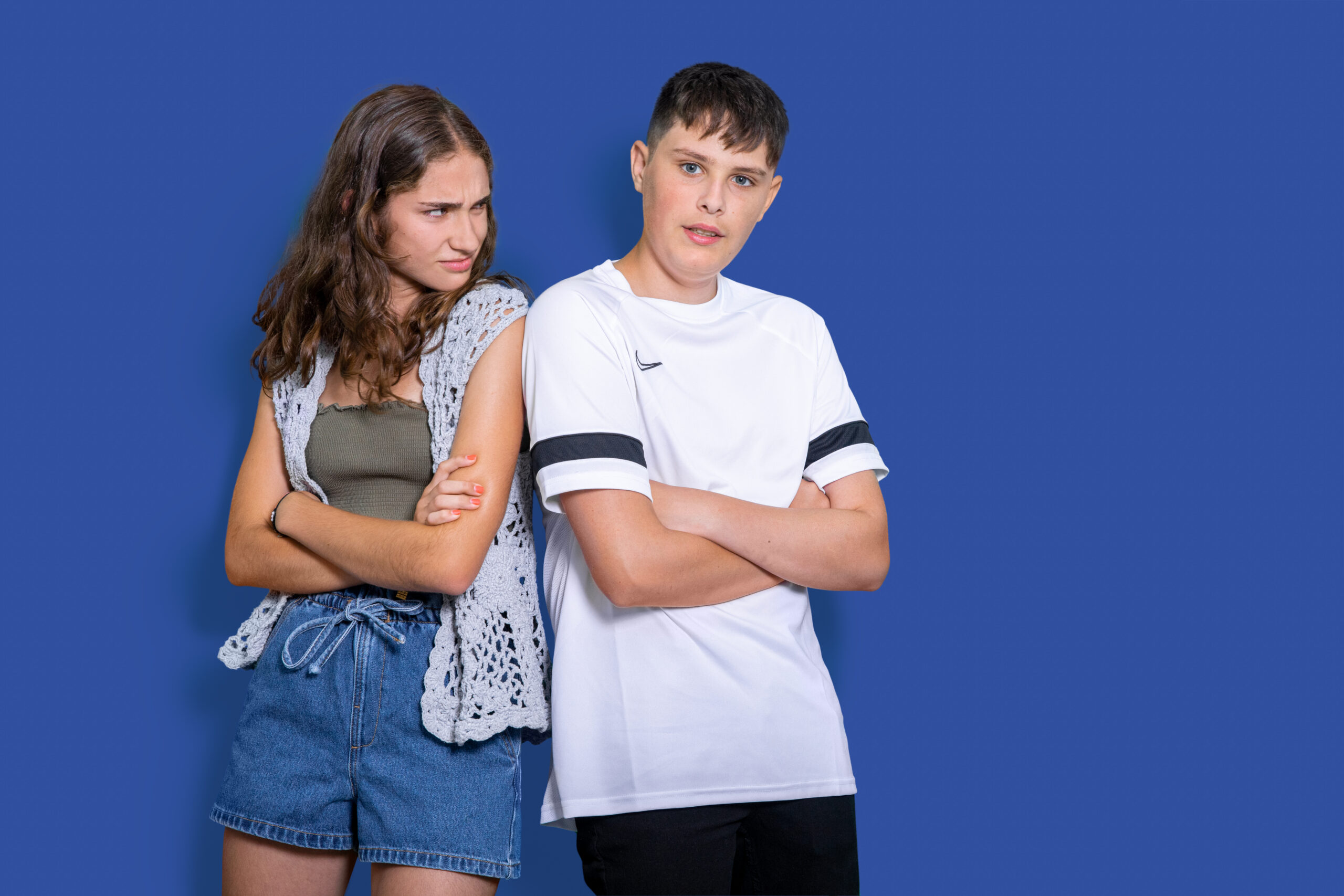 Dos adolescentes con los brazos cruzados y actitud distante, ilustrando la situación de cuando tu hijo adolescente no te habla.